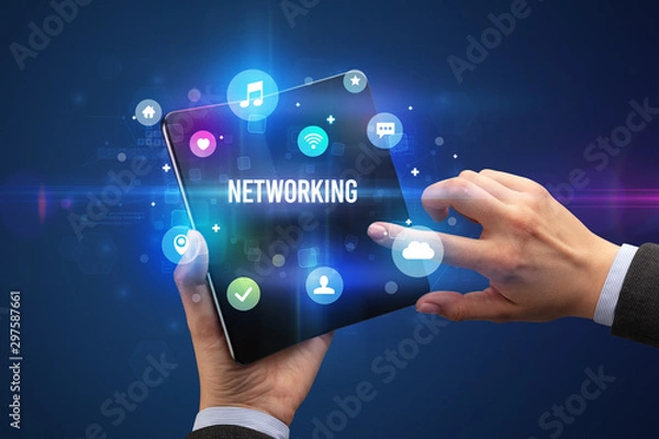 Fototapeta Businessman holding a foldable smartphone with NETWORKING inscription, social media concept