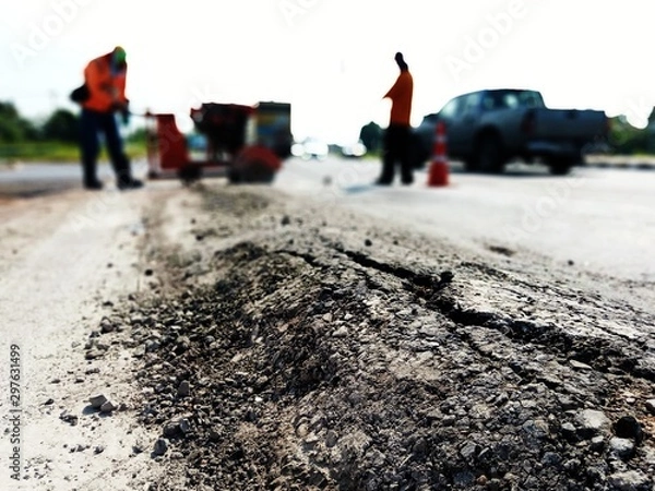 Fototapeta The paved road is damaged. And there are workers fixing the road