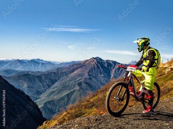 Fototapeta Active man riding downhill mountain bike and looking at mountains