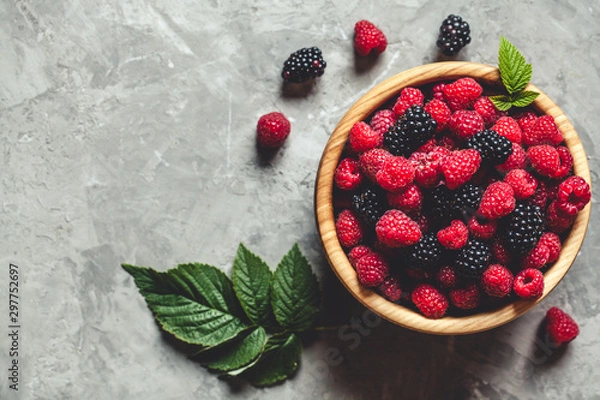 Fototapeta raspberries and blackberries in wood bowl on gray table, vintage
