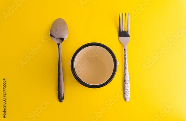 Fototapeta Spoon and fork with yellow background. Soft focus at middle. Dinning Concept.