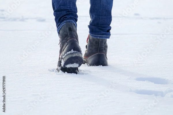 Fototapeta Walking in the snow. Closeup of winter shoes / boots. Man hiking.