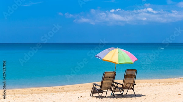 Fototapeta Pair of sun loungers and a beach umbrella on a deserted beach, Beach umbrella on a sunny day, sea in background.