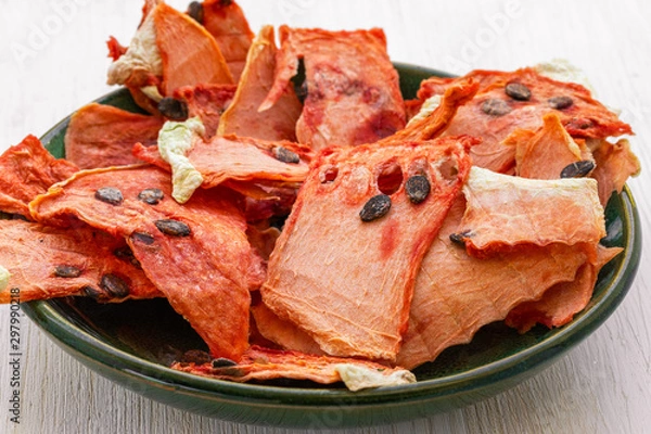 Obraz Dried pulp of watermelon lies on a green plate on a white wooden background, side view from above