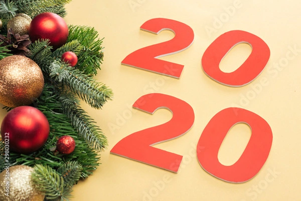 Fototapeta paper 2020 numbers near christmas tree branch with baubles on yellow background
