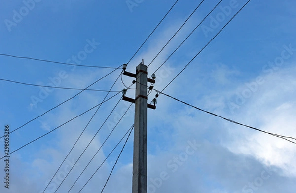 Fototapeta power pole with wires against a blue sky with clouds