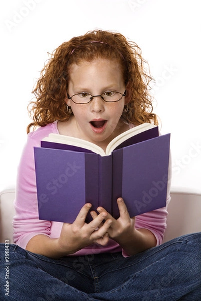 Fototapeta Girl sitting reading book looking surprised.