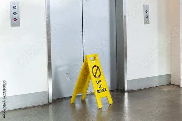 Fototapeta Elevator with an "Out of service" yellow sign in front of it.