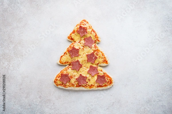 Fototapeta Pizza shaped as Christmas tree with stars made of pepperoni.