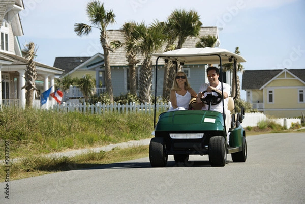 Obraz Dad driving golf cart with mom beside him.