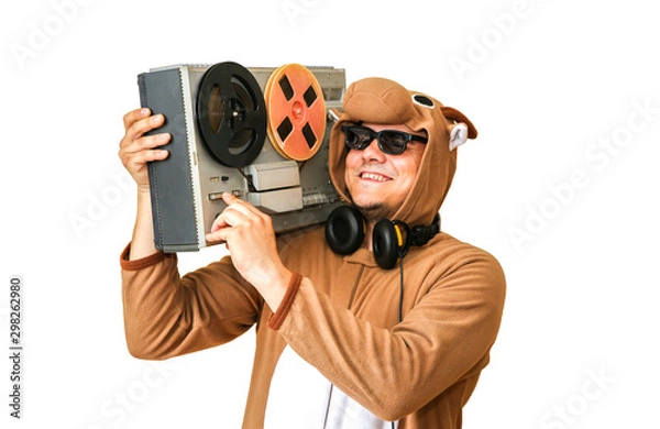 Fototapeta Man in cosplay costume of a cow with reel tape recorder isolated on white background. Guy in the animal pyjamas sleepwear. Funny photo with party ideas. Disco retro music.