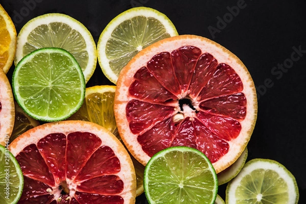 Fototapeta Slices of pink Star Ruby grapefruit and green lime on black background