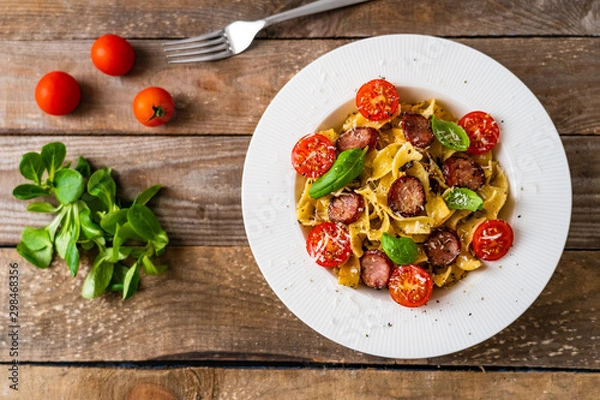 Fototapeta Tagliatelle with sausages on wooden table