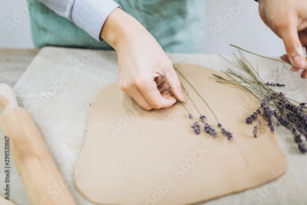 Fototapeta The potter's hands are shaped a cup from a clay. The process of creating pottery. The master ceramist works in his studio. Close-up, only hands. Crockery from clay own hands.