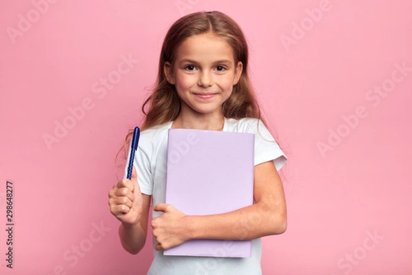 Fototapeta girl holding a book , pen. Back to school concept.isolated pink background, studio shot. lifestyle, free time, kid is ready to study.