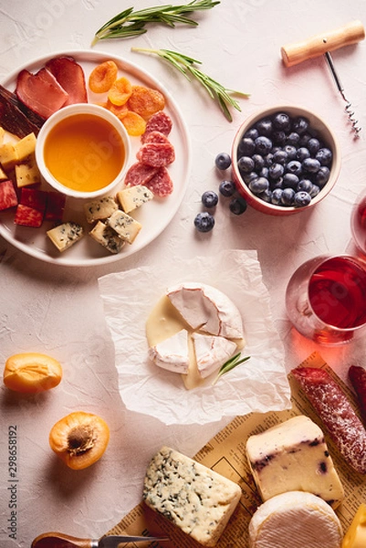 Fototapeta Red wine with different kinds of cheese, charcuterie assortment, crackers, grapes, nuts