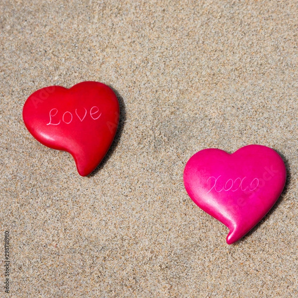 Obraz Two pink and red heart sitting on the sand at the beach