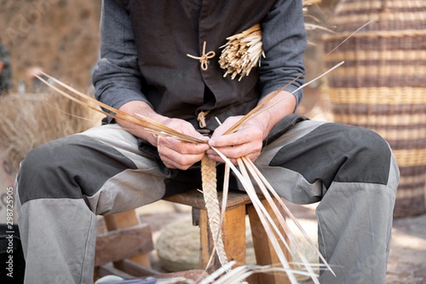 Obraz old wicker craftsman with hands working in isolated foreground.