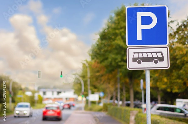 Fototapeta A rectangular blue and white sign with the letter P for parking. This parking is for buses only. A city street in the evening with cars and cloudy sky.