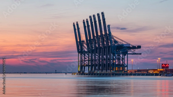 Obraz Row of container terminal cranes at red colored sunset in Port of Antwerp, Belgium