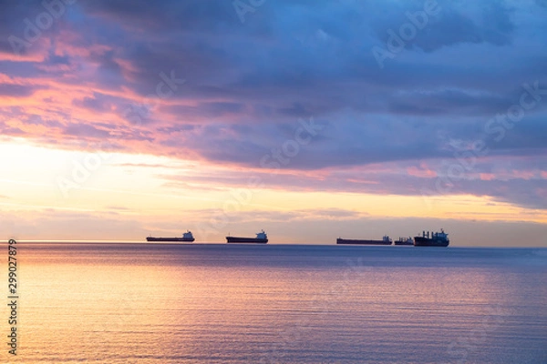 Fototapeta Scene of ocean at the sunset with cloudy and ships as background.Concept of to calm yourself down from stress, depress and clean up mind.Sun light on the left present bring the light of life up.