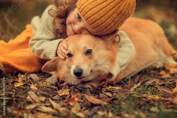 Obraz portrait of girl hugging corgi in the park