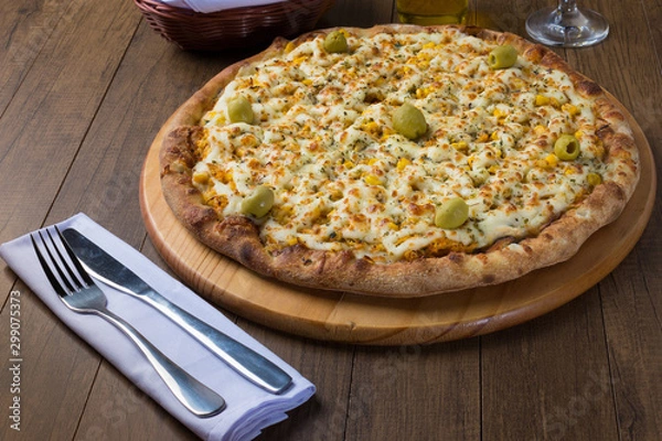 Obraz Delicious Pizza Chicken Catupiry flavor served on a wooden board. Made with Mozzarella, Chicken, Creamy Curd, Green Olives, Corn and Red Tomato Sauce. Fork and Knife on White Napkin 2.