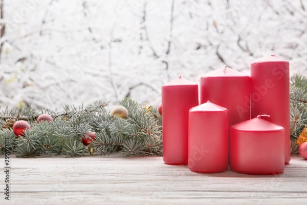 Fototapeta Vintage lantern red candles with Christmas fir tree garland on wooden board on window sill over nature snowing tree park background with copy space