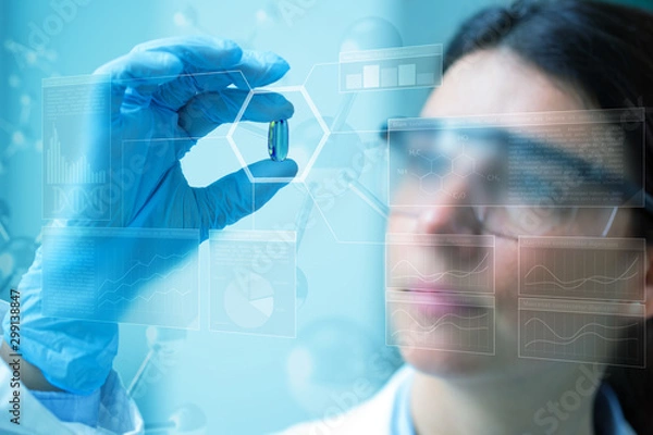 Fototapeta scientist holding a pill behind a scientific blue screen