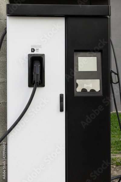 Fototapeta Modern electrical fast charger to hybrid automobiles. High technology charger for green way of driving PHEV. Ecology friendly charger. New generation of environmental friendly green petrol station.