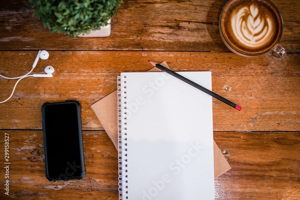Fototapeta Blank notebook and smart phone with coffee on wooden table