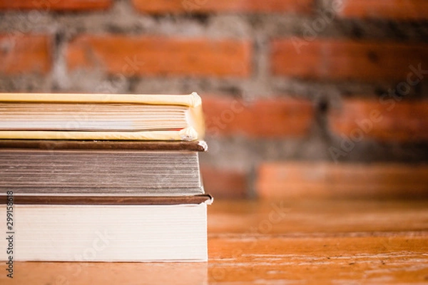 Fototapeta Old books on a wooden shelf with wall brick background