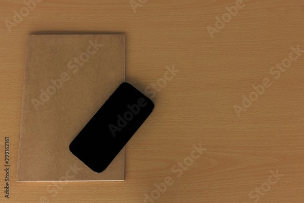 Fototapeta Note book with smart phone on wood table