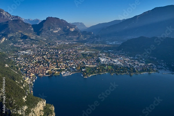 Fototapeta Aerial view of the city of Riva del Garda, Italy. Panoramic view of Lake Garda in the foreground, the city is surrounded by rocks and alpine mountains. Autumn season.