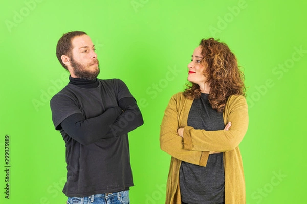 Fototapeta Beautiful young couple skeptic and nervous, disapproving expression on face with crossed arms over green background. Negative person.