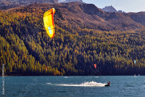 Obraz Mountain landscape with a lot of kite surfers and windsurfers moving in a lake.