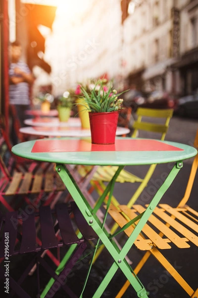 Fototapeta Multi-colored table of a street cafe with a perspective view of the street