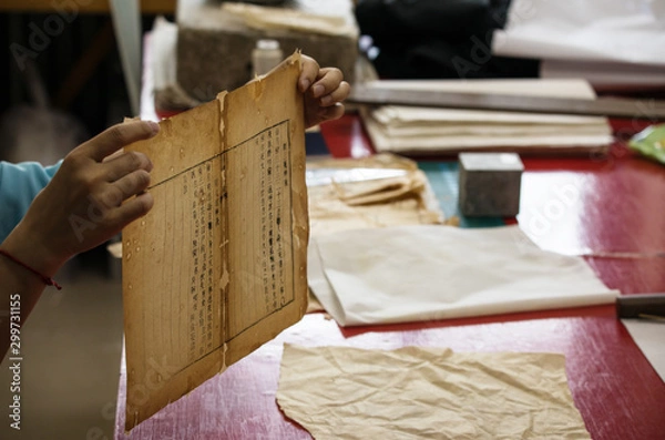 Fototapeta Traditional Chinese book and calligraphy restorer laboratory. Master hands at work close-up.