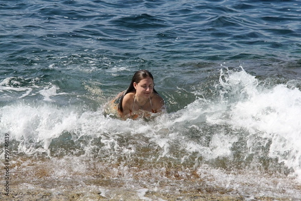 Obraz A girl swims in the sea off the coast