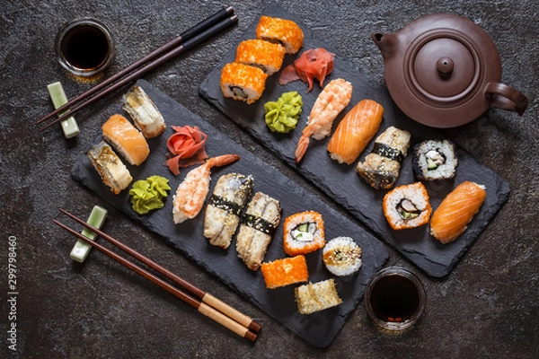 Fototapeta sushi rolls with rice and fish, soy sauce on a dark stone background