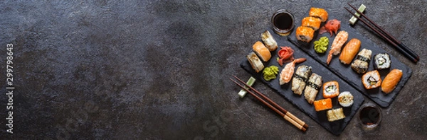 Fototapeta sushi rolls with rice and fish, soy sauce on a dark stone background