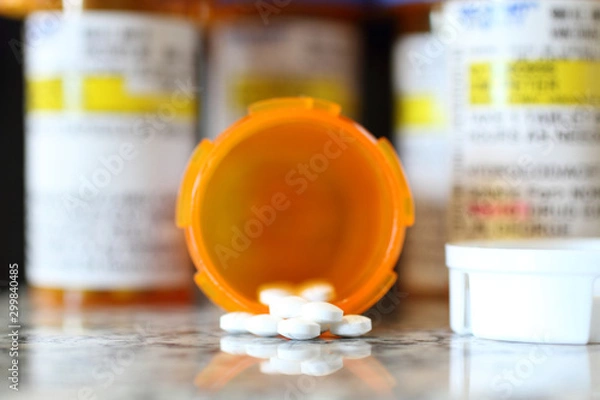 Fototapeta Precription bottles of pain pills on a granite countertop. 