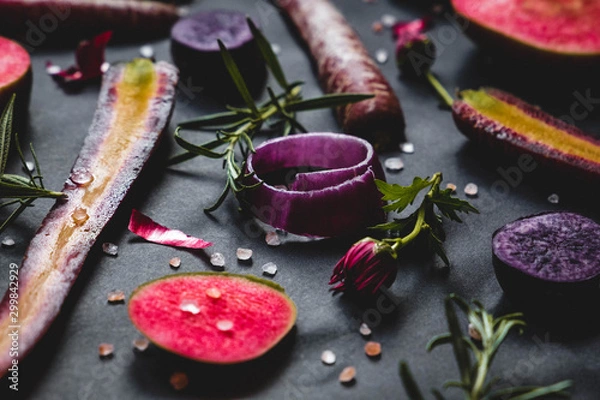 Fototapeta Fruit and vegetable set on black background: red moon apples, purple haze carrots, onion rings, rosemary, flowers