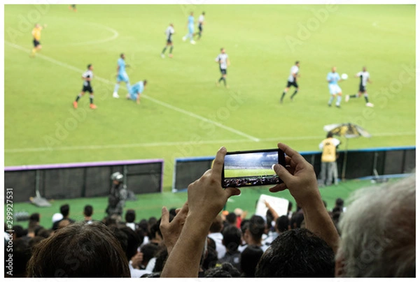 Obraz Man recording a soccer match on Brazil with his mobile phone