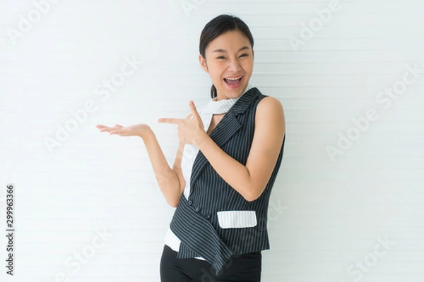 Fototapeta Asian beautiful young woman smile presenting with one hand on upper right side empty and left hand pointing. looking at camera in studio Isolated on white background. Advertisement& presentation conce