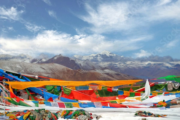 Fototapeta Tibetan praying flags in front of the Yamdrok Lake, reflecting the brown colors of Mt. Naiqinkangsang against a blue clear sky.