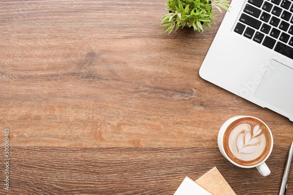 Fototapeta Drewniany stół biurowy z komputerem laptopa, kubek latte Cofee i notatnik z piórem. Widok z góry z przestrzenią kopiowania, płaski Lay.