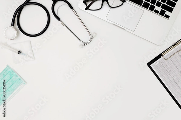 Fototapeta Stethoscope, Top view of doctor's desk table, blank paper on white background, above view doctor work tools on white, Stethoscope, laptop, eyeglass and medical drug on white background, 