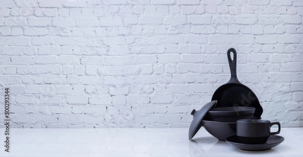 Obraz Black kitchenware on white brick wall texture background.