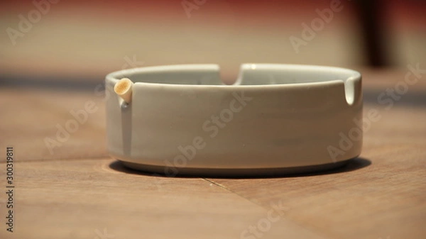 Fototapeta cigarette ashtray on the table, in a photo with a blurry background and selective focus